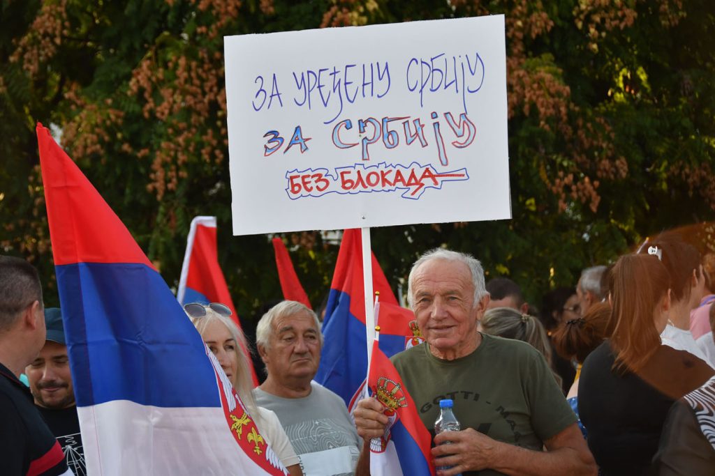 Čovek sa transparentom na skupu protiv blokada