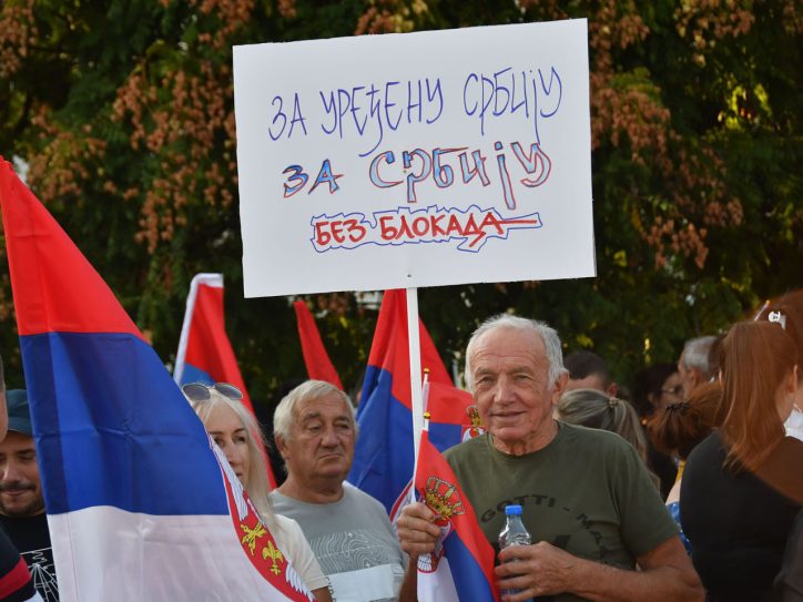 Čovek sa transparentom na skupu protiv blokada