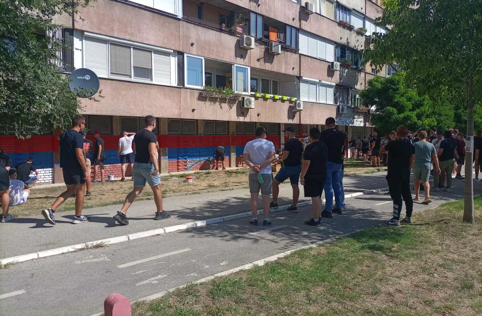 Muškarci u crnom crtaju trobojke po zgradama