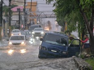 Ljudi napuštaju automobil na u ulici poplavljenoj kišama izazvanim tropskom olujom Melisa u Santo Domingu, Dominikanska Republika