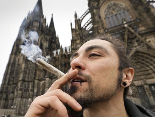 Mlad muškarac puši džoint ispred katedrale u Kelnu