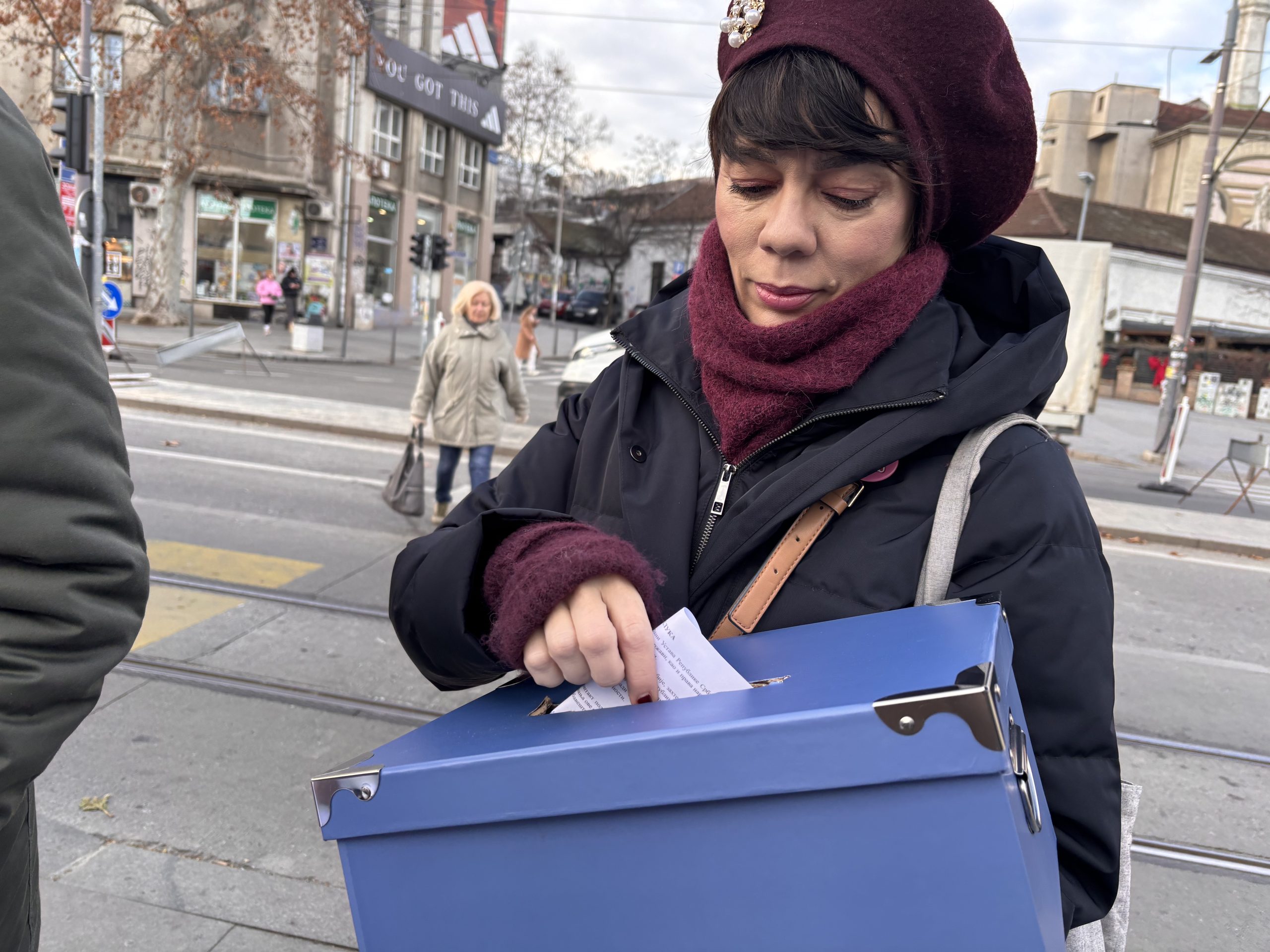 Žena s kutijom u ruci, ubacuje listić