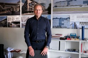 Čovek stoji s rukama na naslonu stolice