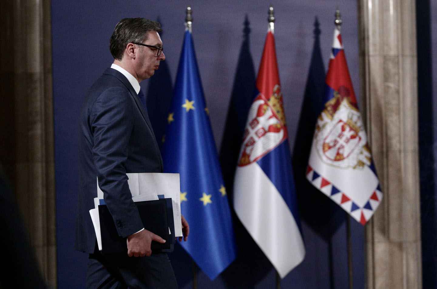 Aleksandar Vučić hoda, iza njega zastave Srbije i EU