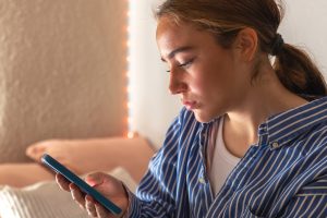 Devojka čita poruku na mobilnom telefonu