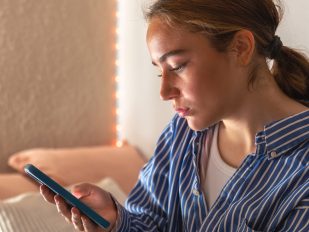 Devojka čita poruku na mobilnom telefonu