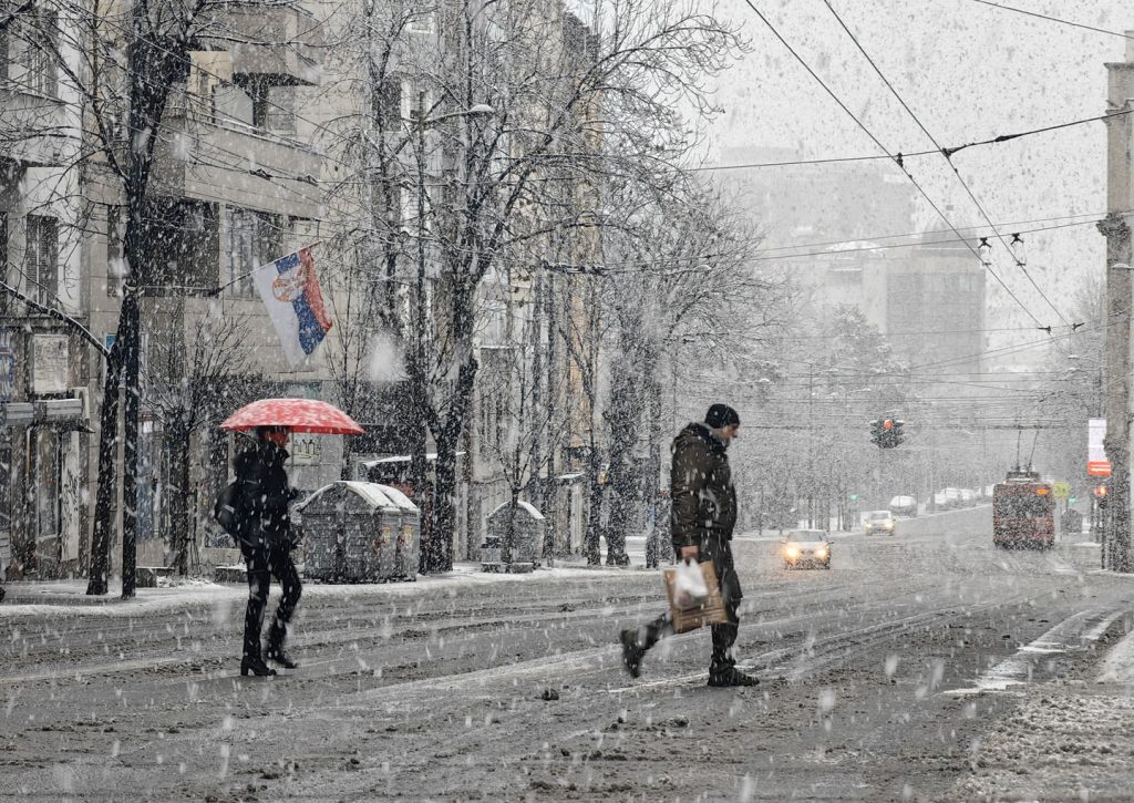 Ljudi prelaze ulicu dok pada jak sneg.