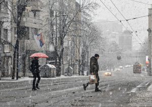 Ljudi prelaze ulicu dok pada jak sneg.