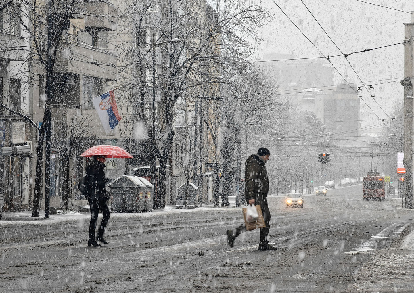 Ljudi prelaze ulicu dok pada jak sneg.