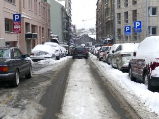 Zavejana parkirana vozila, jedno ide ulicom