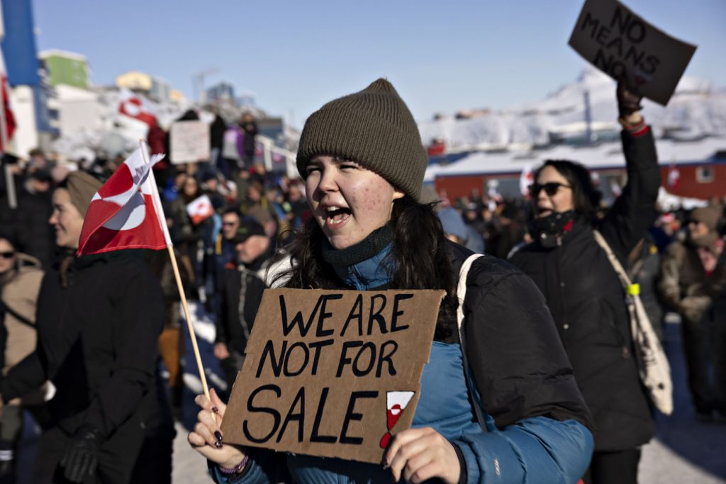 Devojka sa kapom protestuje na Grenlandu sa natpisom 