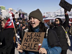 Devojka sa kapom protestuje na Grenlandu sa natpisom 