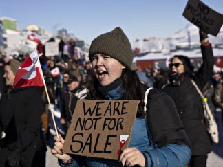 Devojka sa kapom protestuje na Grenlandu sa natpisom 