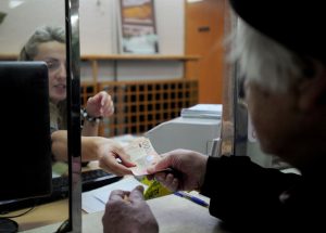 Penzioner na šalteru pošte, novac u rukama njega i radnice