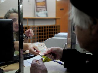 Penzioner na šalteru pošte, novac u rukama njega i radnice