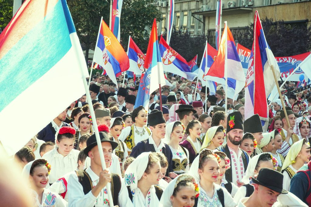 Mladi ljudi u srpskim narodnim nošnjama sa mnogo srpskih zastava