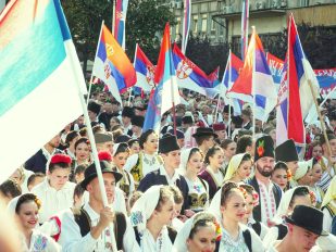Mladi ljudi u srpskim narodnim nošnjama sa mnogo srpskih zastava