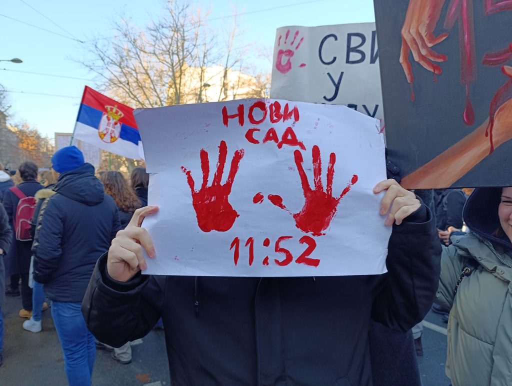 Čovek na protestu s transparentom 