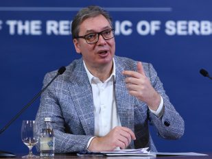 Čovek s naočarima gestikulira dok govori.