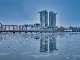 Odsjaj dva solitera na zaleđenom jezeru na kome se nalaze ptice