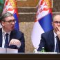 Predsednik Srbije Aleksandar Vučić i premijer Đuro Macut u odelima sa kravatom. U pozadini dve zastave Srbije.