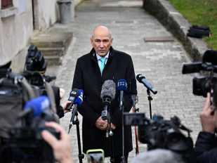 Janez Janša u kaputu sa kravatom okružen mikrofonima i kamerama