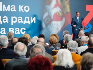 Predsednik Srbije Aleksandar Vučić u sali punoj starijih ljudi slikanim s leđa. Na bini dominira natpis 