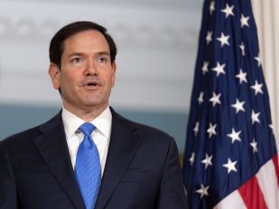 Državni sekretar SAD Marko Rubio ispred američke zastave u tamnoplavopm odelu sa svetloplavom kravatom