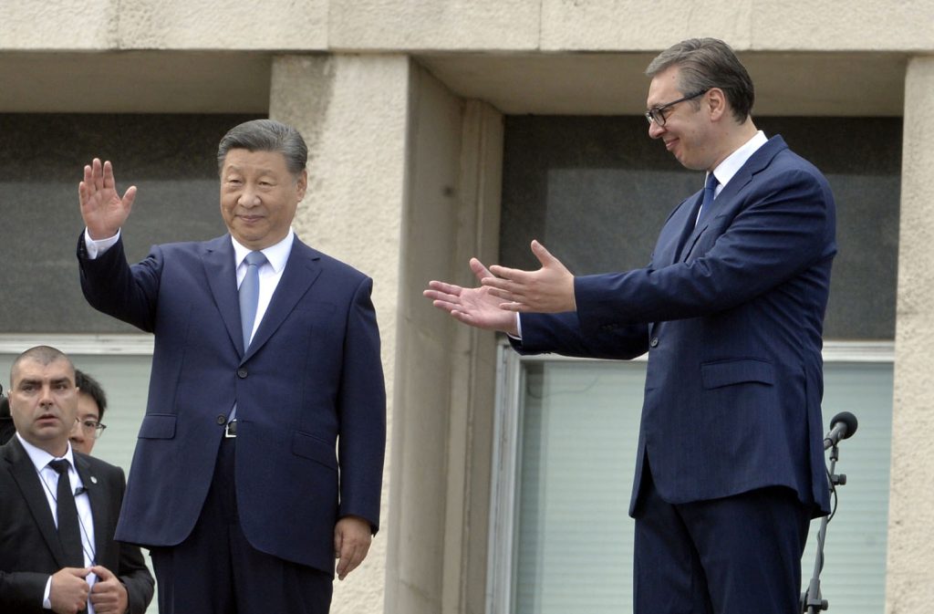Si Đinping u tamnom odelu maše a Aleksandar Vučić u tamnom odelu rukama pokazuje na njega