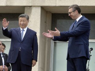 Si Đinping u tamnom odelu maše a Aleksandar Vučić u tamnom odelu rukama pokazuje na njega