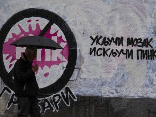 Čovek sa kišobranom prolazi pored grafita 