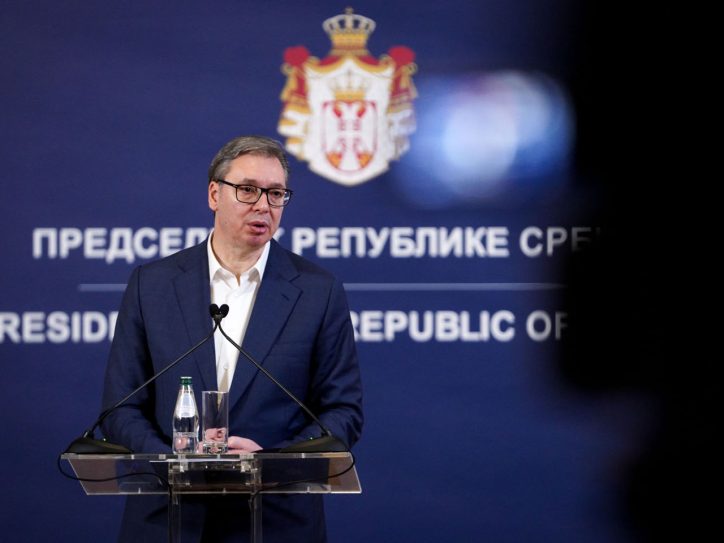 Aleksandar Vučić u teget odelu bez kravata, iza njega grb Srbije