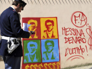 Italijanski policajac posmatra grafit na zidu katedrale u Palermu na kom je prikazan Mateo Mesina Denaro, jedan od organizatora najtežih ubistava sicilijanske mafije.