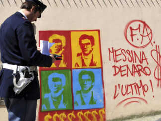 Italijanski policajac posmatra grafit na zidu katedrale u Palermu na kom je prikazan Mateo Mesina Denaro, jedan od organizatora najtežih ubistava sicilijanske mafije.