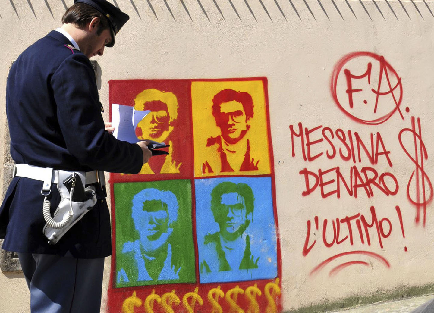 Italijanski policajac posmatra grafit na zidu katedrale u Palermu na kom je prikazan Mateo Mesina Denaro, jedan od organizatora najtežih ubistava sicilijanske mafije.