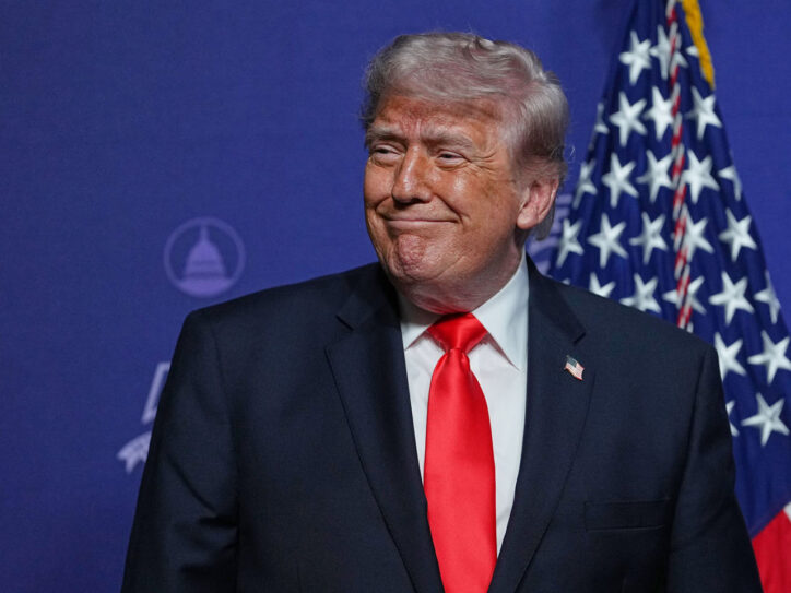 Predsednik SAD Donald Tramp se kezi sa tamni sakoom, crvenom kravatom i američkom zastavom u pozadini