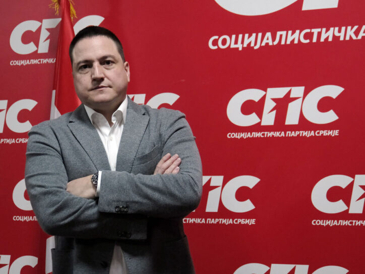 Funkcioner SPS-a Branko Ružić ispred velikog crvenog transparenta na kome piše Socijalistička partija Srbije