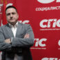 Funkcioner SPS-a Branko Ružić ispred velikog crvenog transparenta na kome piše Socijalistička partija Srbije