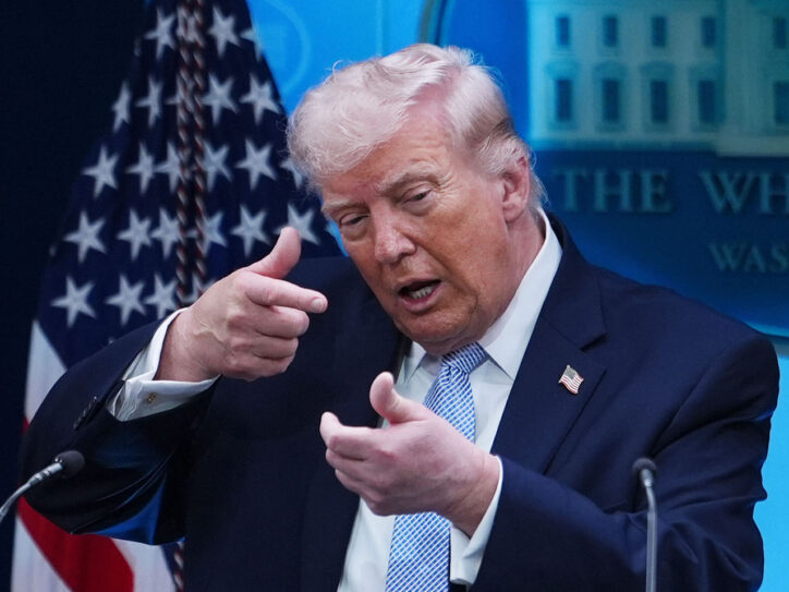 Predsednik SAD Donalkd Tramp pokazuje rukama da nišani ispred američke zastave