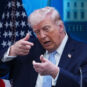 Predsednik SAD Donalkd Tramp pokazuje rukama da nišani ispred američke zastave
