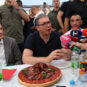 Aleksandar Vučić sedi za stolom pod šatorom, pred njim meze, sokovi i mikrofovni televizija